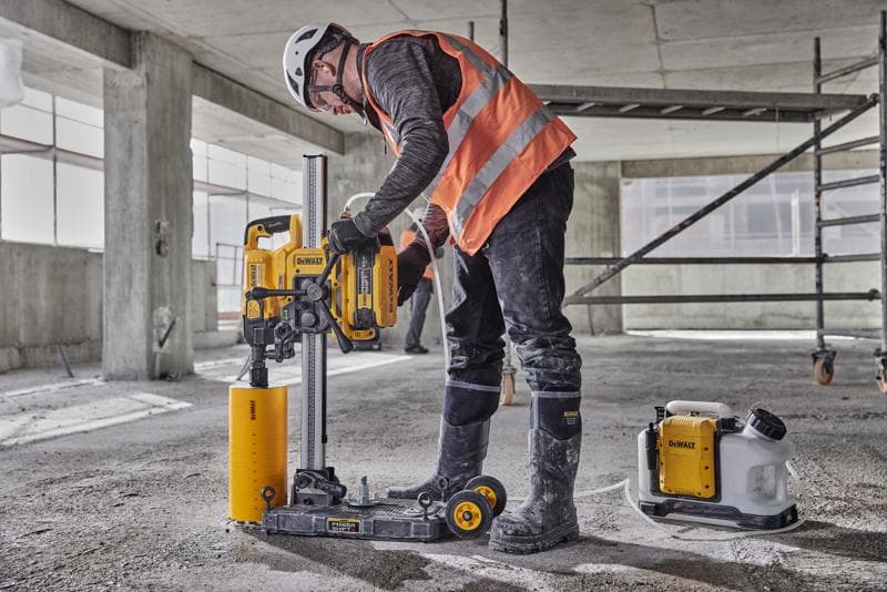 Arbeiter nutzt DEWALT DCPS151 Betonbohrmaschine auf Baustelle, mit Schutzausrüstung und Helm.