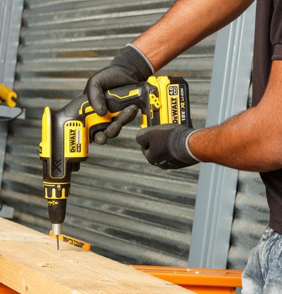 Person nutzt DEWALT DCF620NT-XJ Akku-Schraubendreher zum Bohren in Holz, mit Handschuhen.