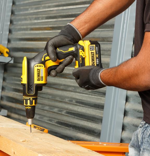 Person nutzt DEWALT DCF620NT-XJ Akku-Schraubendreher zum Bohren in Holz, mit Handschuhen.